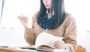 単語帳で英語の試験勉強をしている女子高校生