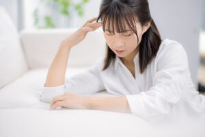 体調不良でソファーによりかかる女性