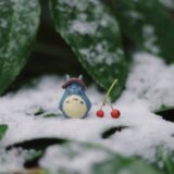 雪の中に置かれたトトロ人形と木の実